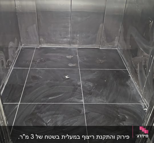 רצפת אריחים שחורים במעלית בתהליך שיפוץ
